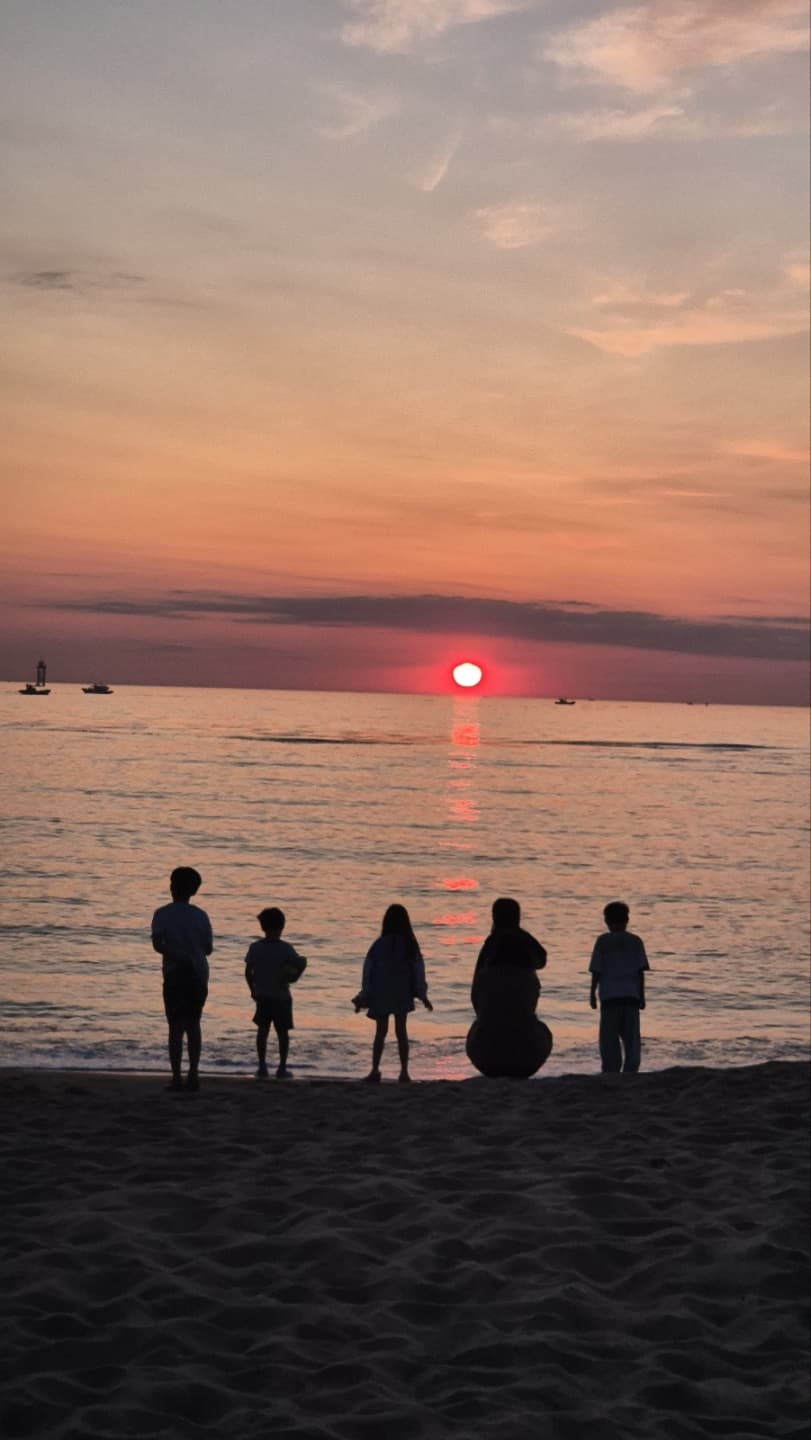 새벽 해변에서 일출을 맞는 아이들